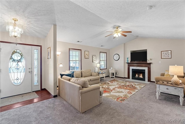 carpeted living room featuring lofted ceiling, a fireplace with flush hearth, visible vents, and a textured ceiling