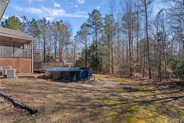 view of yard featuring a deck, central AC, and a covered pool