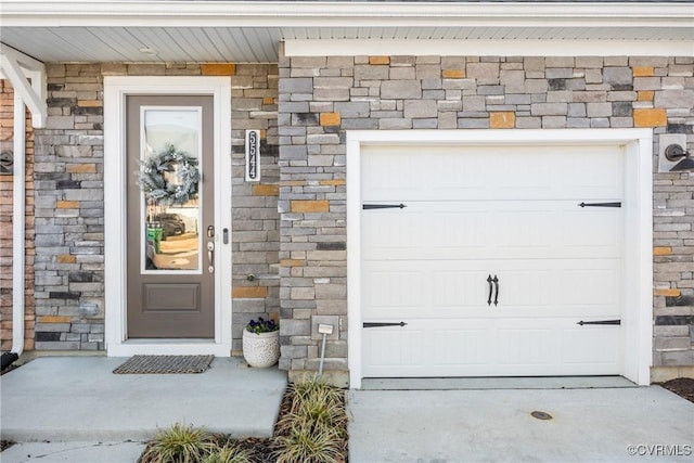 entrance to property with a garage and stone siding