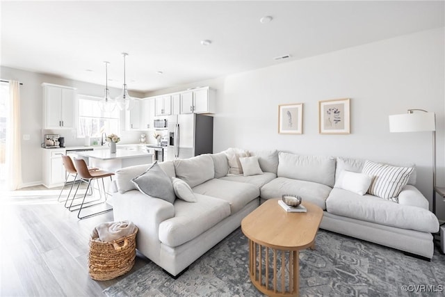 living area featuring light wood-style flooring and visible vents