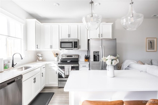 kitchen with white cabinets, appliances with stainless steel finishes, light countertops, and a sink