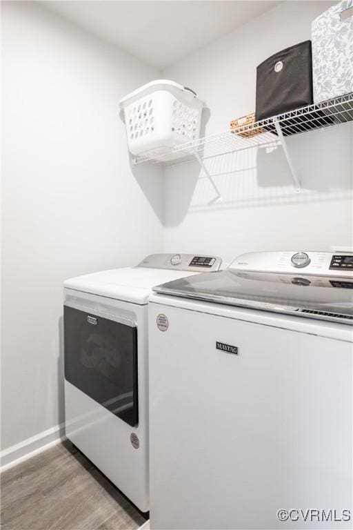 washroom with washing machine and dryer, laundry area, light wood-style flooring, and baseboards