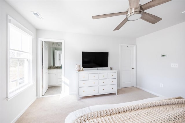 bedroom featuring visible vents, baseboards, ensuite bathroom, and light colored carpet