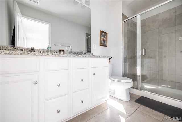 full bath with double vanity, toilet, a sink, a shower stall, and tile patterned flooring