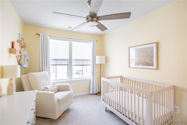 bedroom featuring visible vents, baseboards, ceiling fan, carpet flooring, and a nursery area