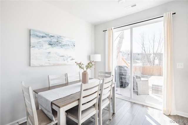 dining space featuring baseboards, visible vents, and wood finished floors