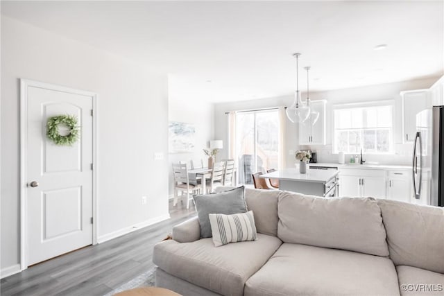 living area featuring an inviting chandelier, wood finished floors, and baseboards