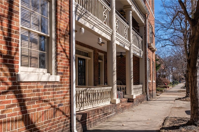 view of side of property featuring a porch, brick siding, and a balcony