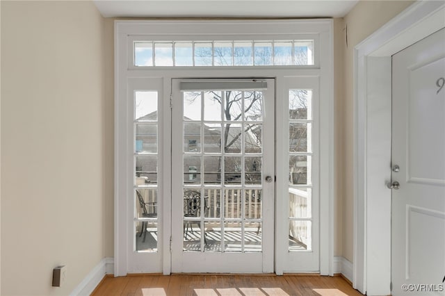 doorway with light wood finished floors and baseboards