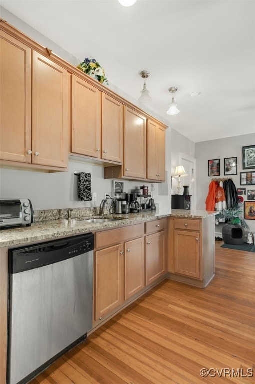 kitchen featuring a toaster, a peninsula, light wood-type flooring, light stone countertops, and dishwasher