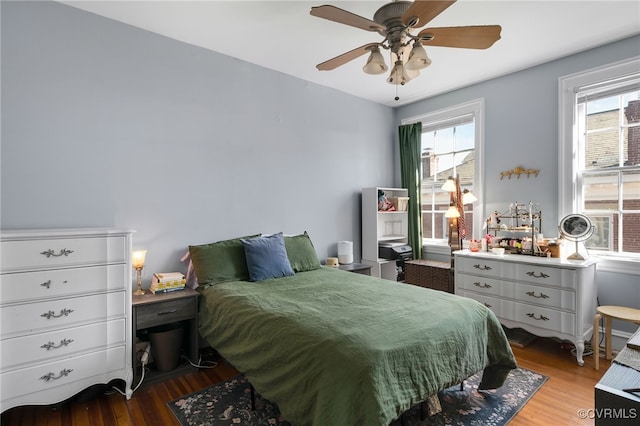 bedroom featuring ceiling fan, multiple windows, and wood finished floors