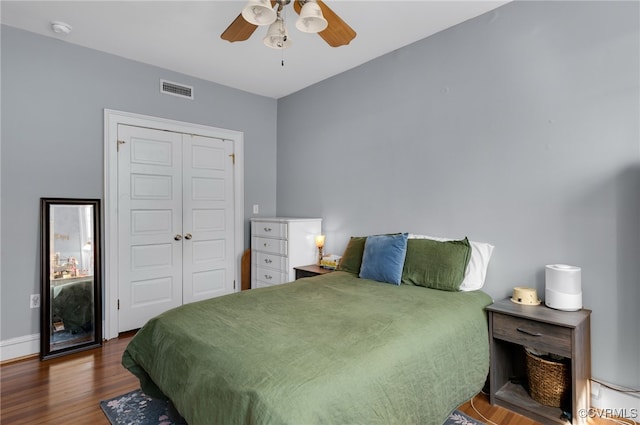 bedroom featuring a closet, visible vents, a ceiling fan, wood finished floors, and baseboards