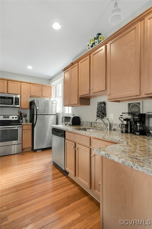 kitchen featuring appliances with stainless steel finishes, light wood-type flooring, a sink, and recessed lighting