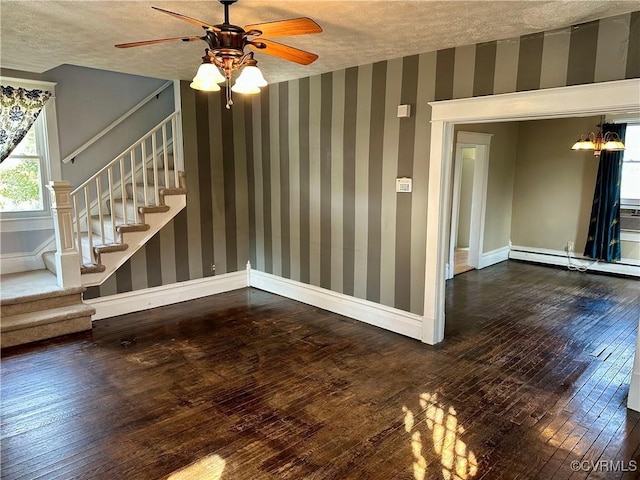 spare room with wallpapered walls, baseboards, wood-type flooring, stairway, and a textured ceiling