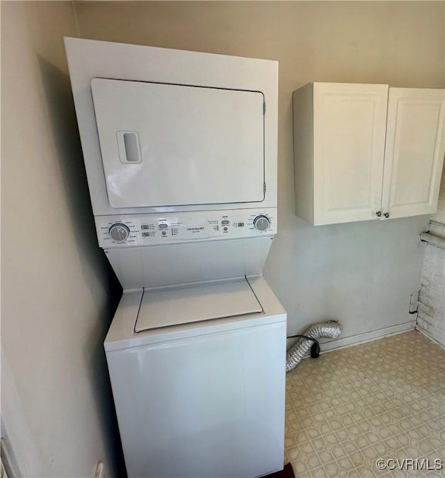 laundry room with stacked washer and dryer, cabinet space, and tile patterned floors