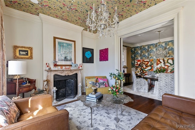 living area featuring a fireplace, ornamental molding, a notable chandelier, and wood finished floors