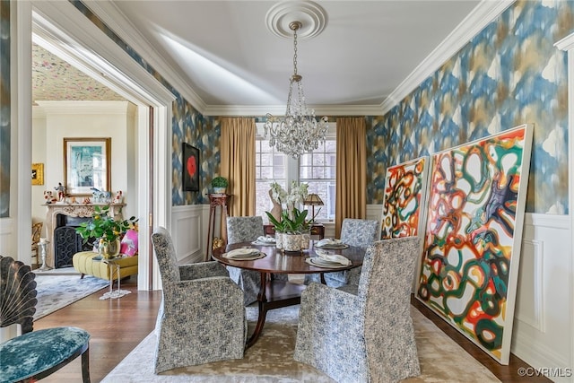 dining area featuring ornamental molding, wainscoting, and wallpapered walls