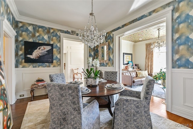 dining room with ornamental molding, wood finished floors, and an inviting chandelier