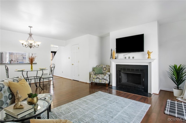 living room with a fireplace with flush hearth, baseboards, a chandelier, and hardwood / wood-style floors