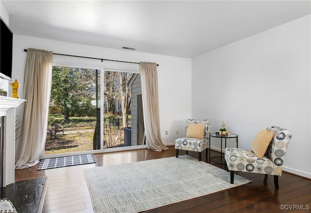 unfurnished room featuring visible vents, a fireplace, baseboards, and wood finished floors