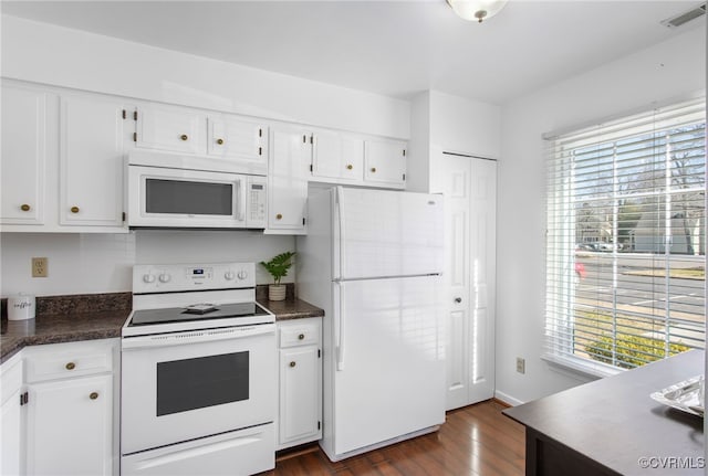 kitchen with plenty of natural light, white appliances, dark countertops, and visible vents