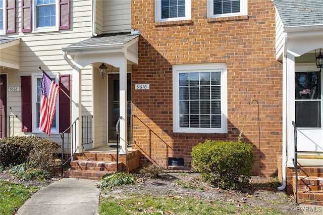 doorway to property featuring crawl space, a shingled roof, and brick siding