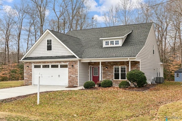 view of front of house featuring roof with shingles, concrete driveway, a front yard, a garage, and stone siding