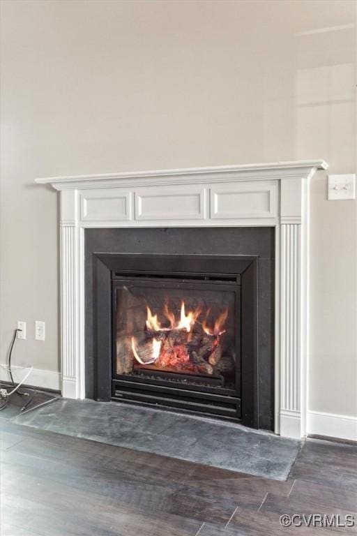 room details with a fireplace with flush hearth, baseboards, and wood finished floors