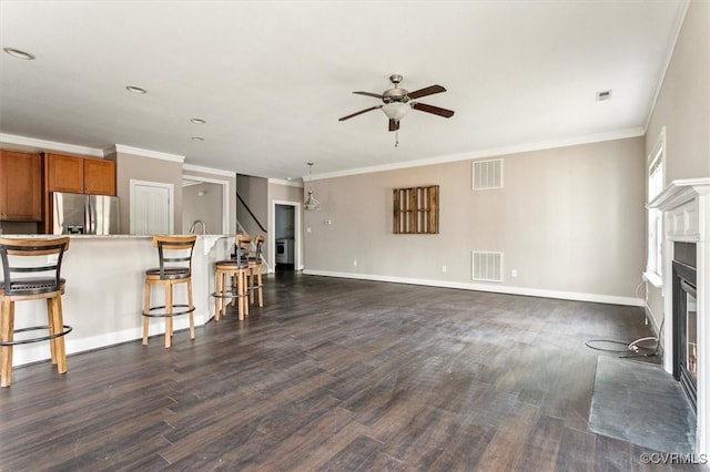 living room with dark wood-type flooring, a glass covered fireplace, visible vents, and baseboards