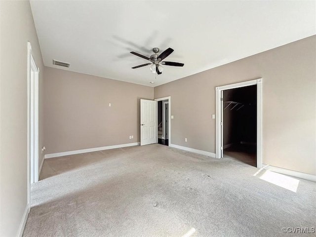 unfurnished bedroom featuring visible vents, a spacious closet, a ceiling fan, light carpet, and baseboards