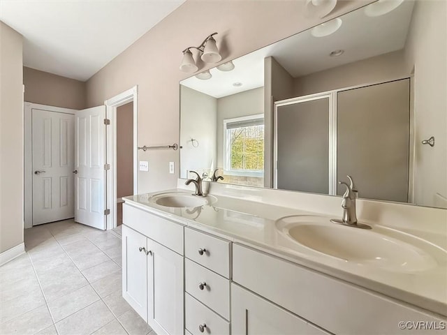 full bathroom featuring a stall shower, double vanity, a sink, and tile patterned floors