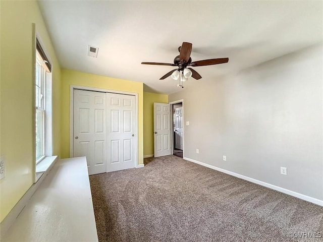 unfurnished bedroom with carpet, a closet, visible vents, a ceiling fan, and baseboards