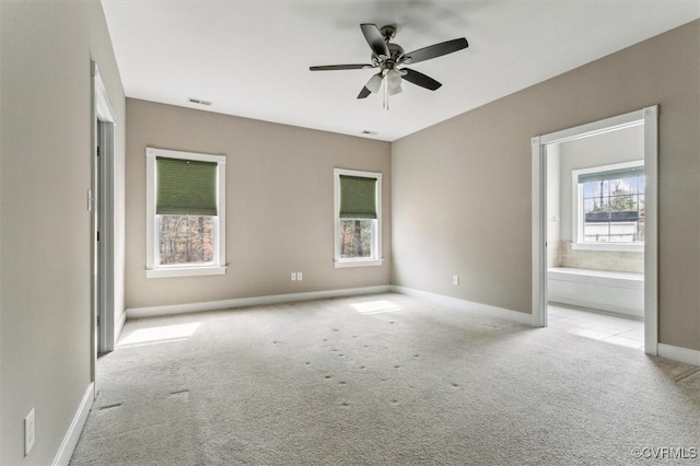 carpeted spare room featuring baseboards, visible vents, and a ceiling fan