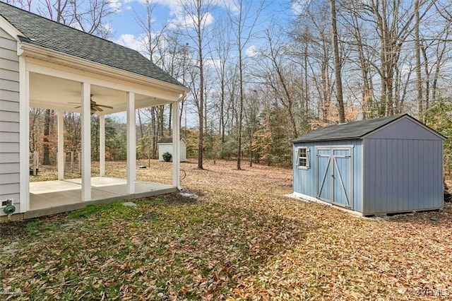 view of yard featuring a storage shed, a ceiling fan, and an outbuilding