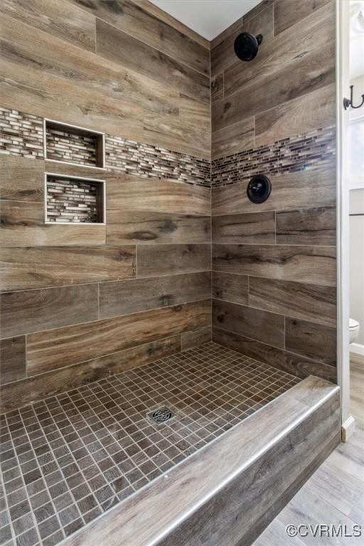 bathroom featuring toilet and a tile shower