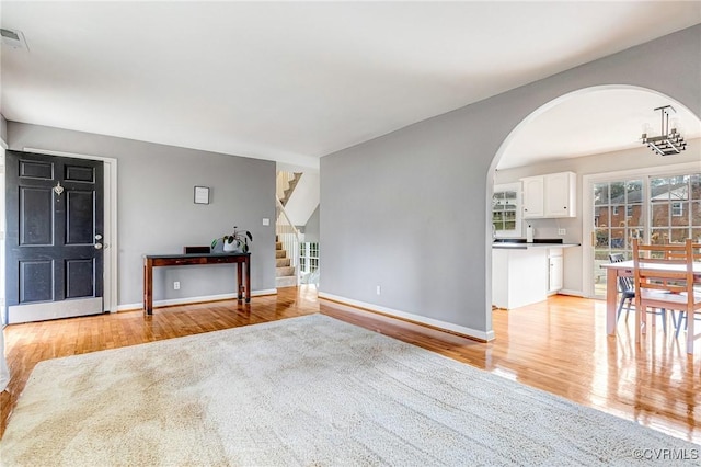 interior space featuring light wood-style flooring, arched walkways, stairway, and baseboards