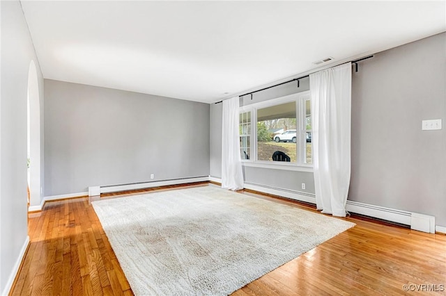 spare room featuring baseboards, a baseboard radiator, visible vents, and wood finished floors