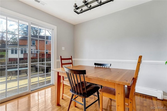 dining space featuring visible vents, a baseboard radiator, light wood-style flooring, and baseboards