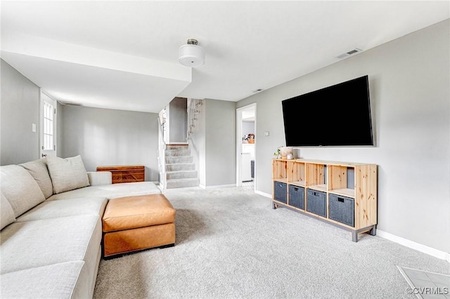 living room featuring carpet, visible vents, baseboards, and stairs