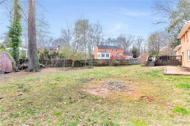 view of yard featuring a shed, fence, an outdoor structure, and a wooden deck