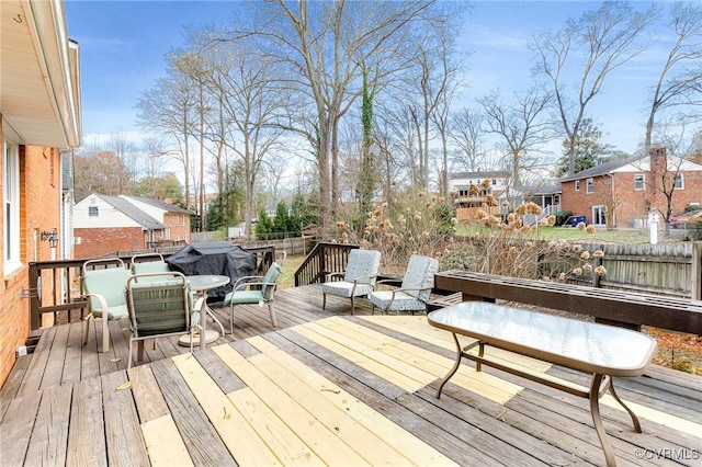 wooden deck with a residential view, a grill, and outdoor dining space