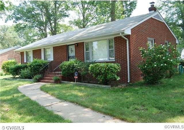 single story home with brick siding, a chimney, and a front lawn