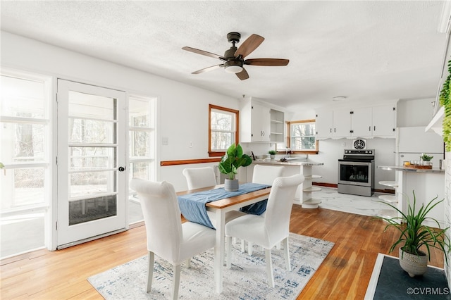 dining space featuring light wood-style floors, ceiling fan, and a textured ceiling