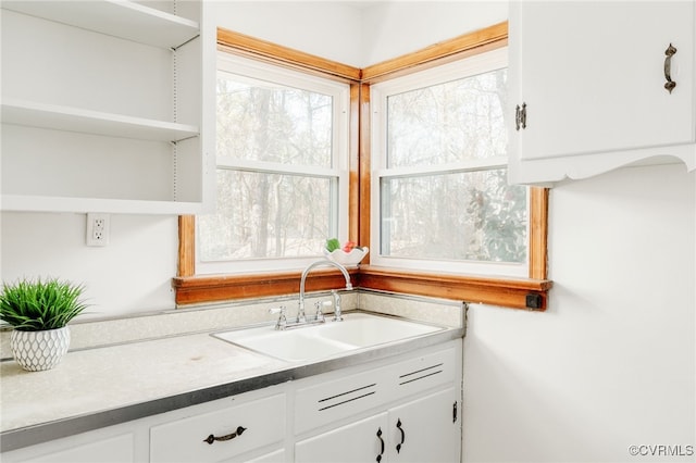 kitchen featuring light countertops, open shelves, a sink, and white cabinets