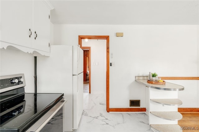 kitchen with marble finish floor, visible vents, electric range, white cabinets, and baseboards