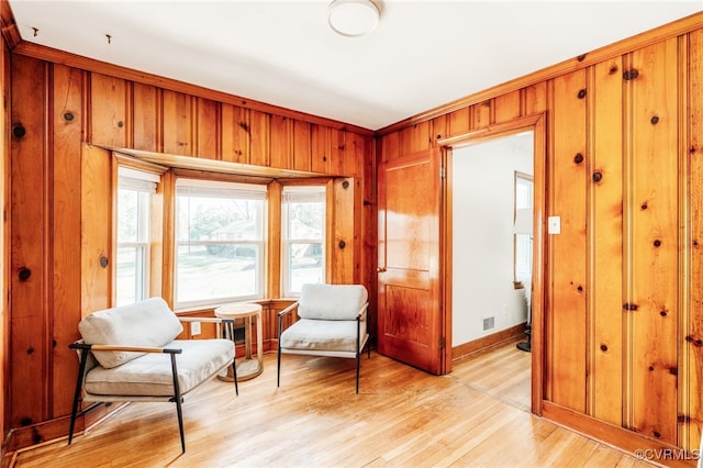 living area with light wood finished floors, wooden walls, and baseboards