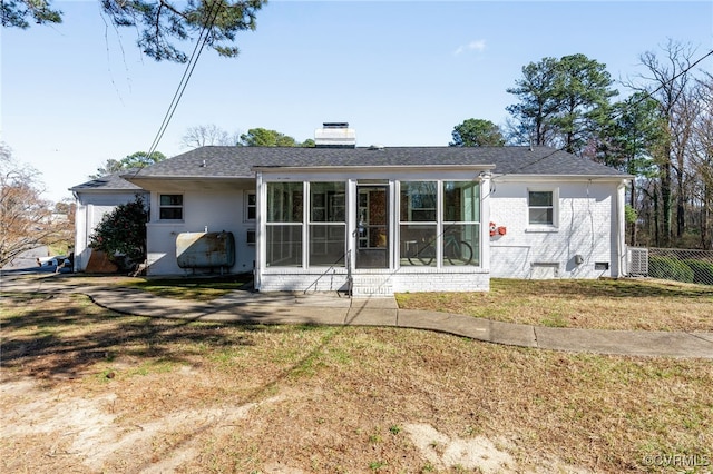 rear view of property with a lawn, a sunroom, a chimney, crawl space, and brick siding