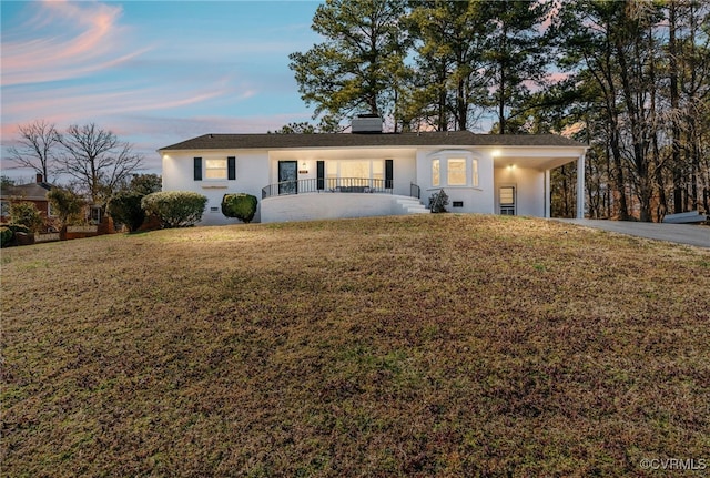 ranch-style home with driveway, a chimney, a front yard, and stucco siding