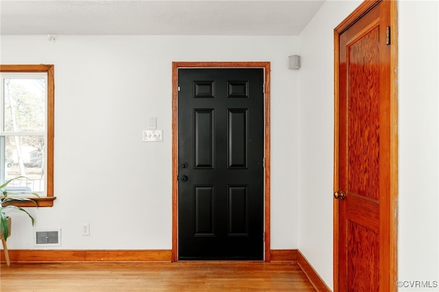 foyer with visible vents, light wood-style flooring, and baseboards