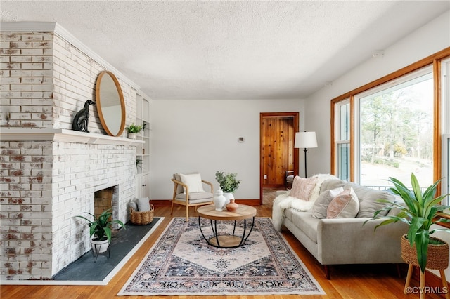 living area with a fireplace, a textured ceiling, and wood finished floors